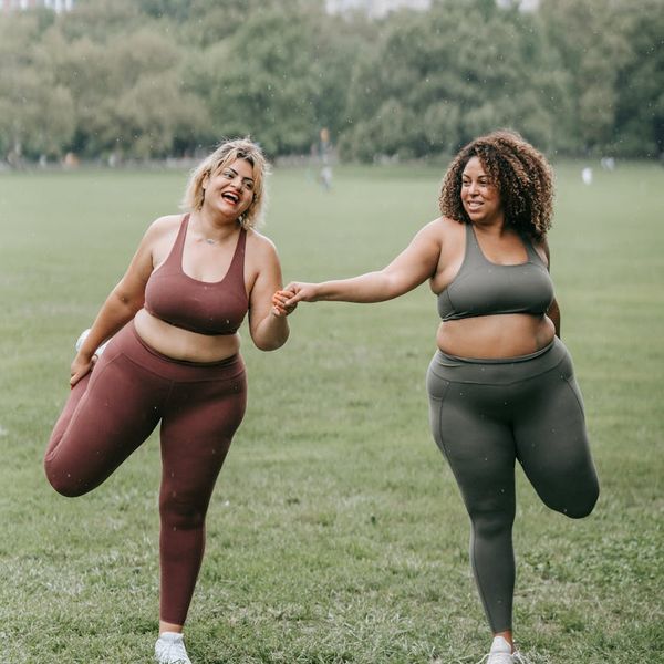 Smiling woman stretching gently outdoors in a park.